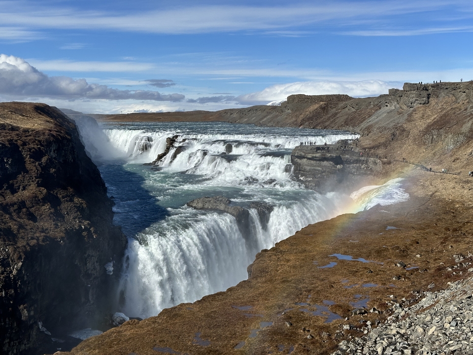 A powerful waterfall cascading into a river with a rainbow.