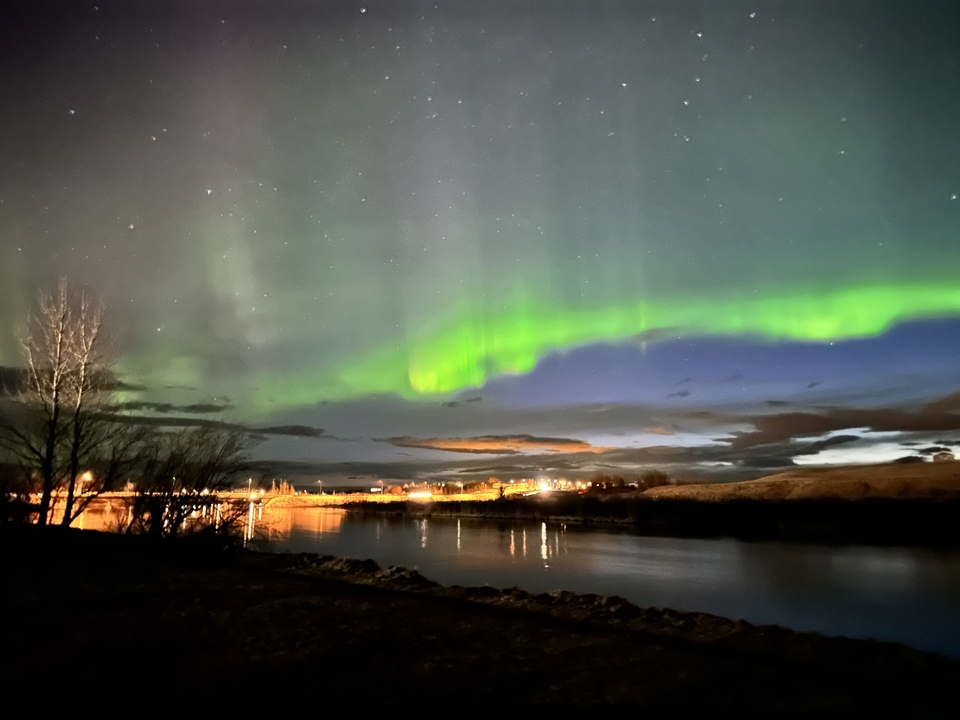 Northern lights illuminating the night sky over a water body.