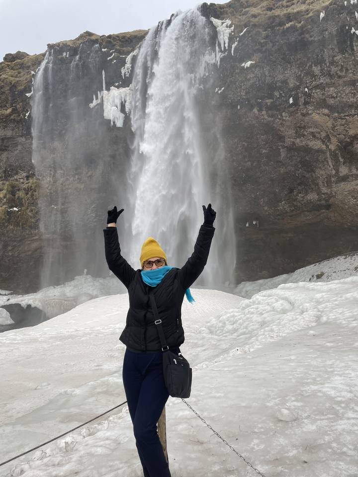 Person posing with a waterfall in winter.