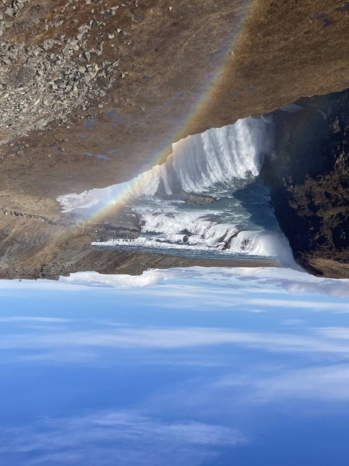 Waterfall with rainbow over rocky landscape