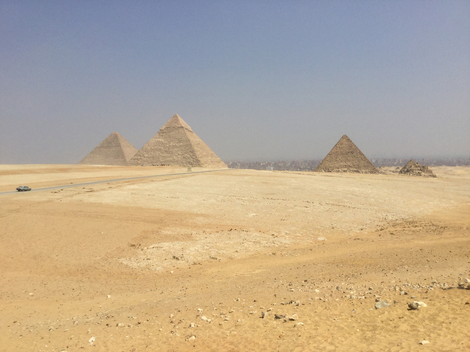 Panoramic view of Giza pyramids in a desert landscape.