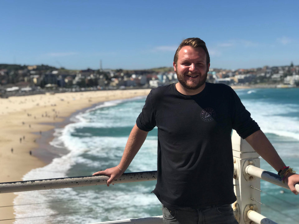Man leaning on a railing overlooking the beach.
