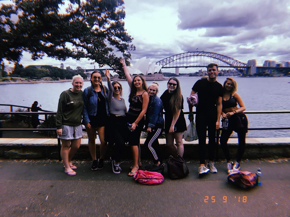 Group of people with Sydney Harbour Bridge and Opera House in the background.