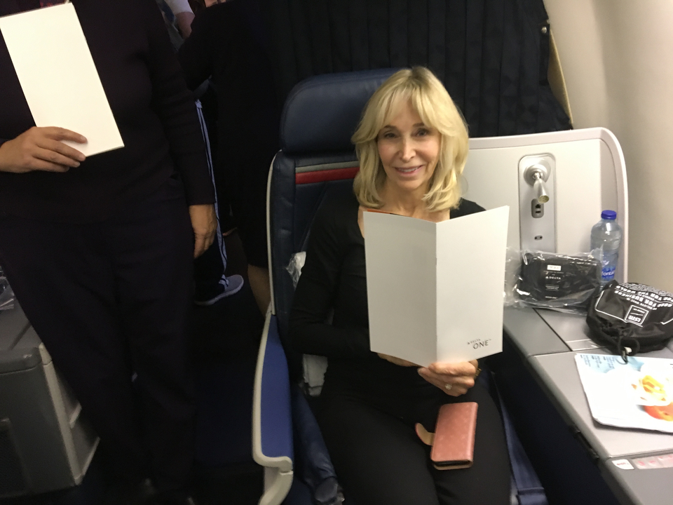Une femme assise dans la cabine d'un avion tenant un menu.