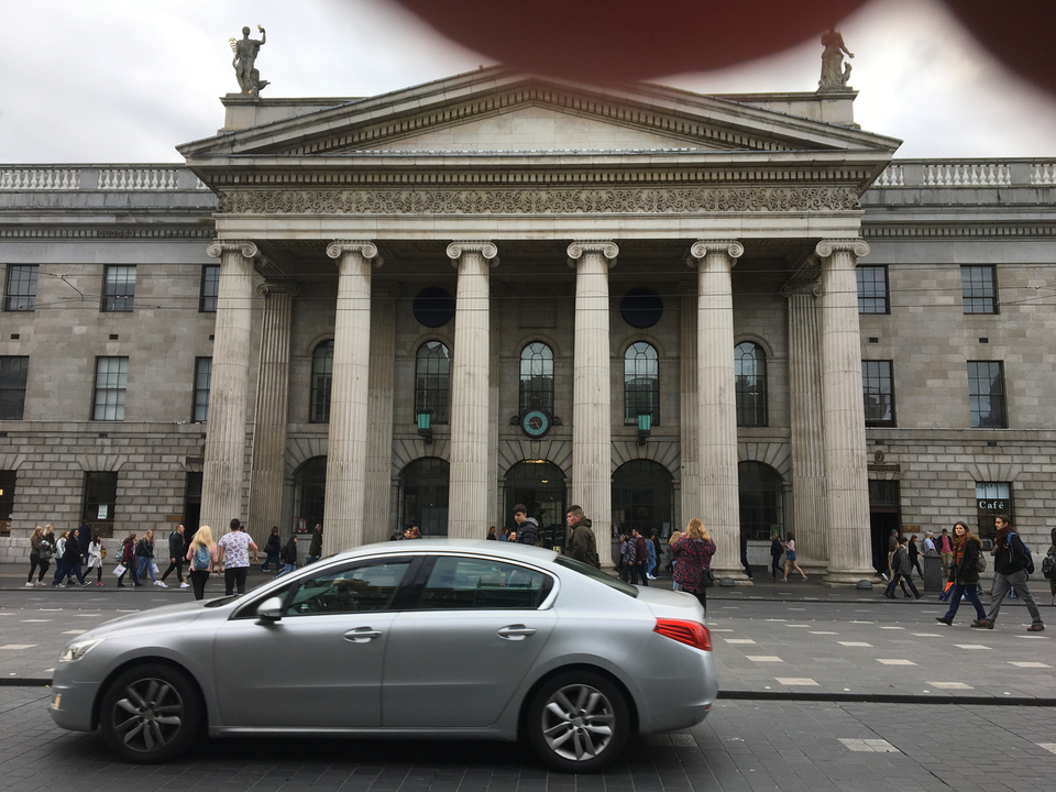 Grand bâtiment avec des colonnes et des gens qui marchent