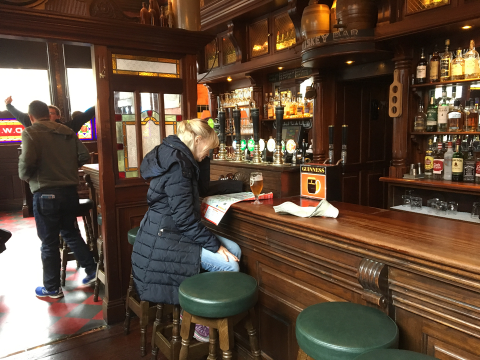 Personne assise à un bar avec une pinte de Guinness