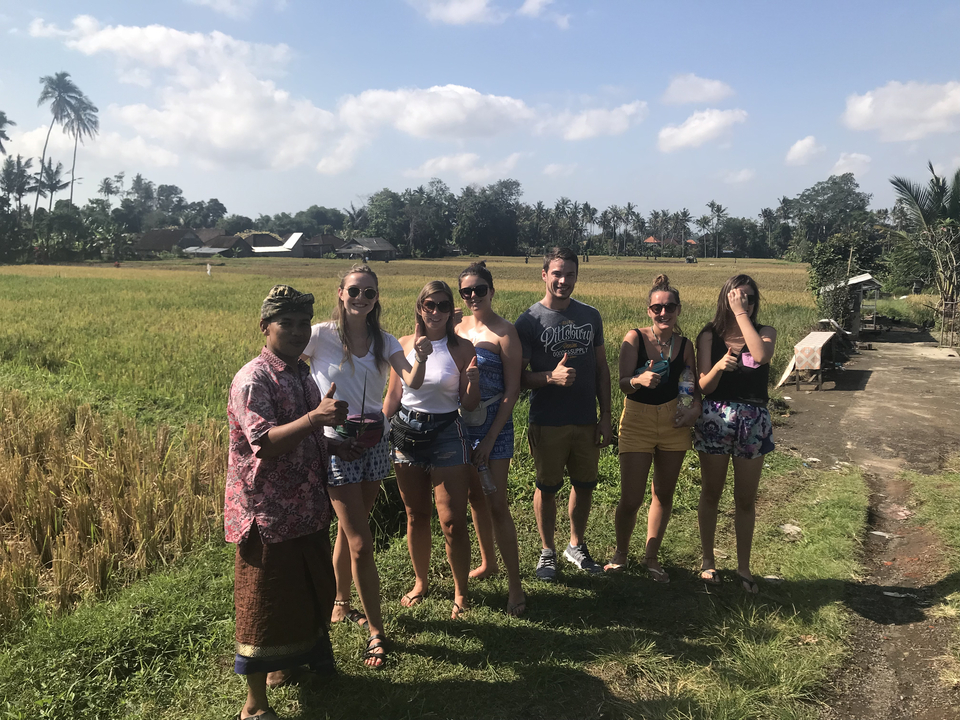 Group of people posing in a field with palms in the distance.