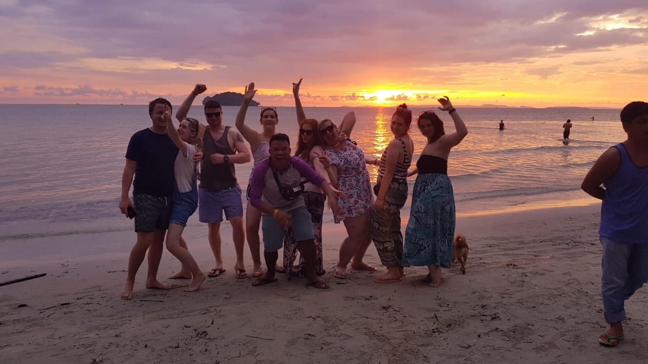 Groupe d'amis posant sur la plage au coucher du soleil.