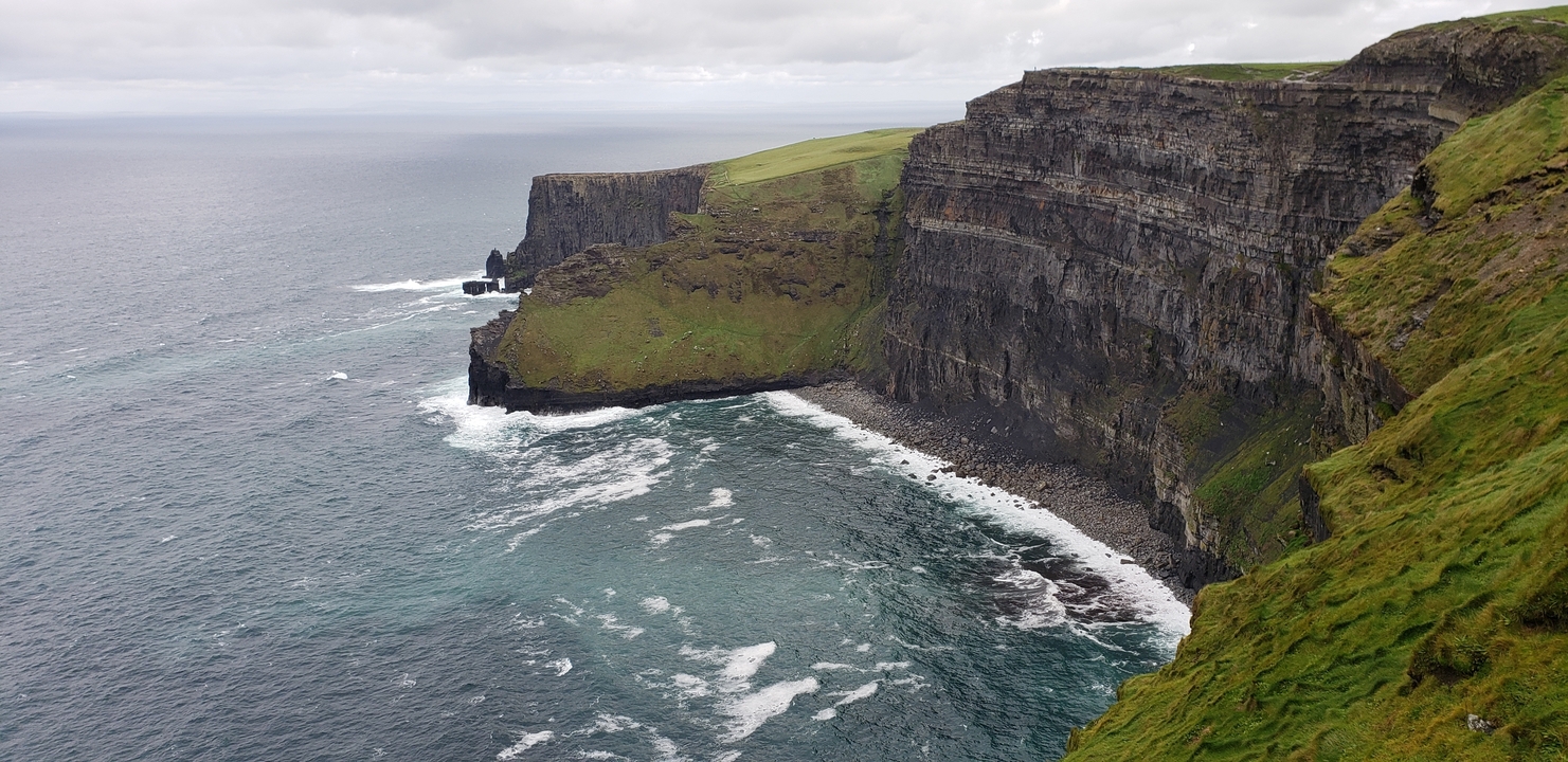 Dramatic coastal cliffs with turbulent sea below.