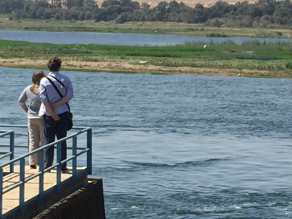 Couple debout sur un quai surplombant une rivière.