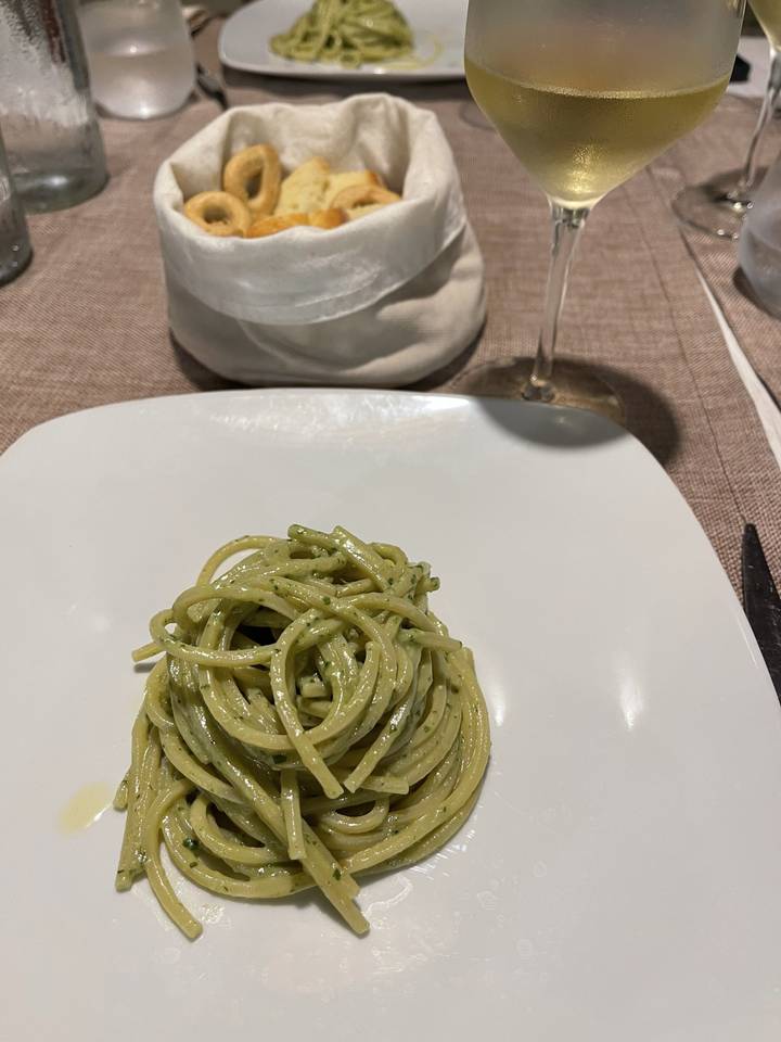 Plate of pasta with a glass of wine on a table.