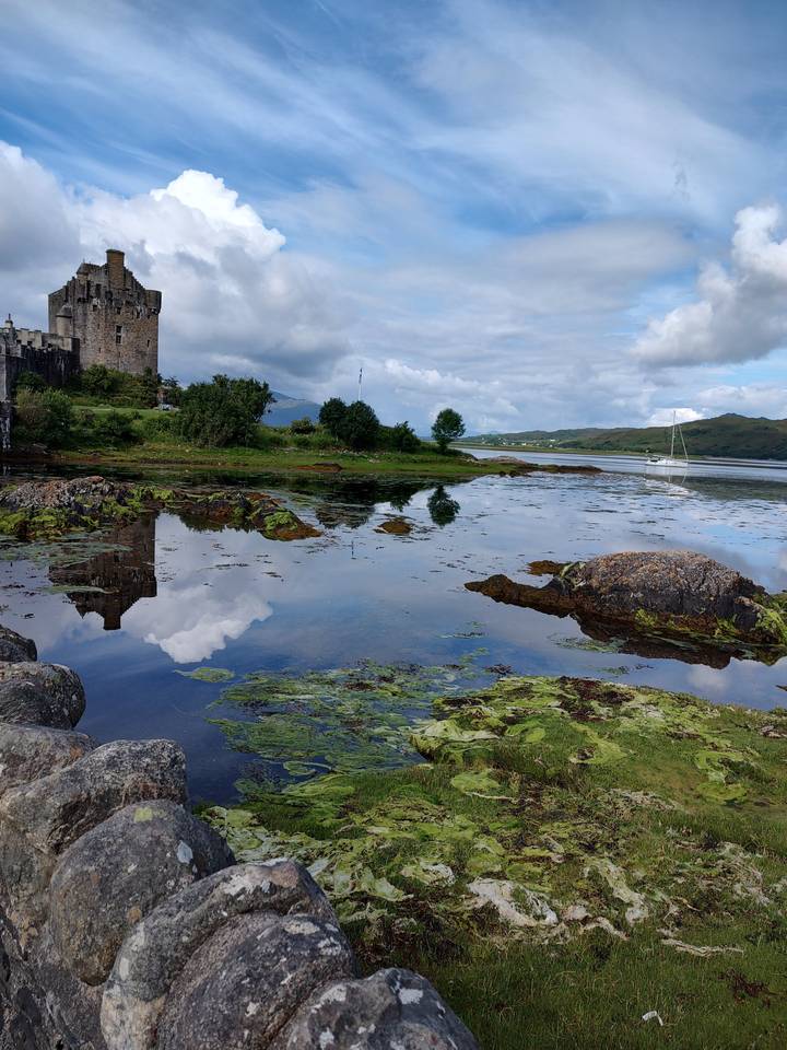 Castle by a water body with a reflection of clouds.