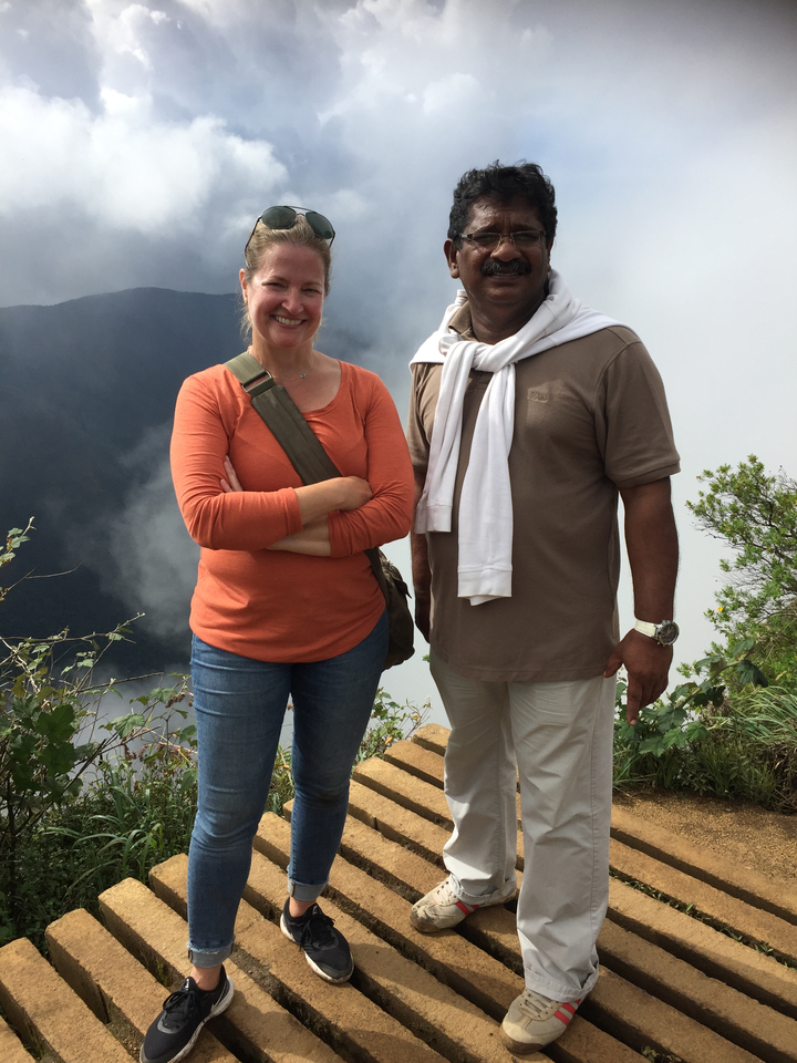 Deux personnes posant devant un paysage pittoresque avec du brouillard et de la végétation.