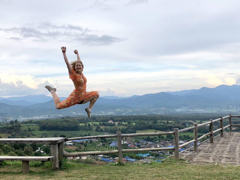 A person in mid-air with a scenic landscape in the background.