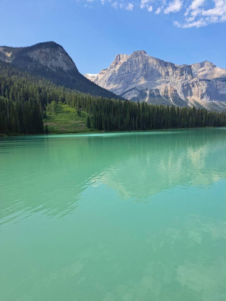 Turquoise lake with forested banks and towering mountains.