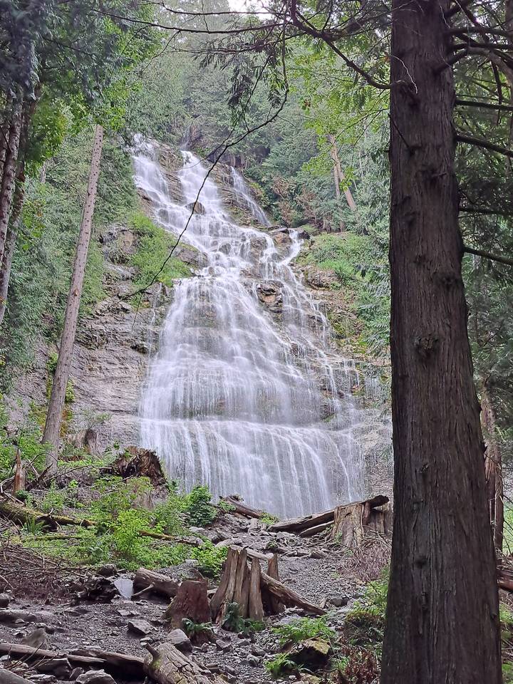 Waterfall cascading down a cliff surrounded by forest.