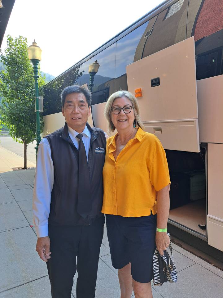 Two people posing next to a bus.