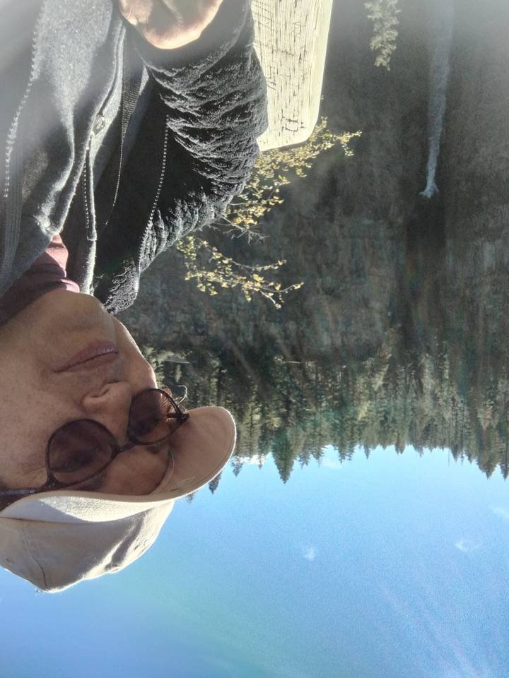 Selfie with a view of trees and cliffs in the background.