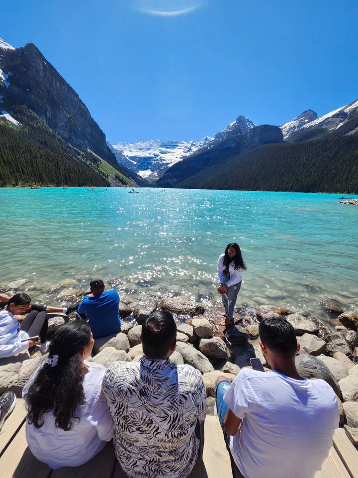 Group gathered by a scenic turquoise lake with mountains.
