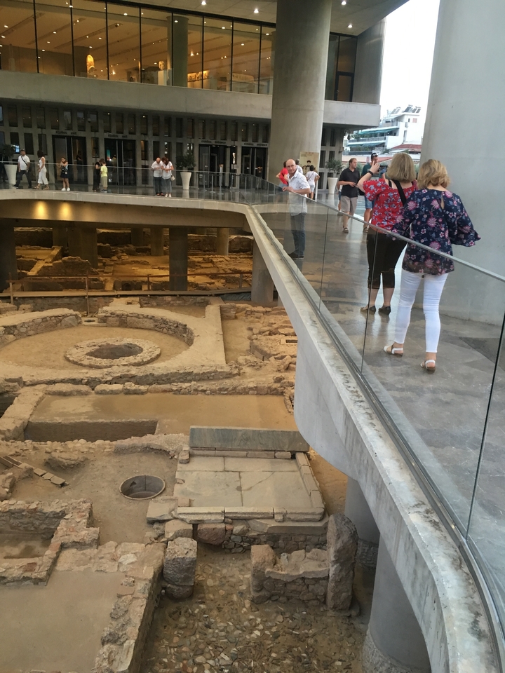 People walking above ancient ruins inside a museum.