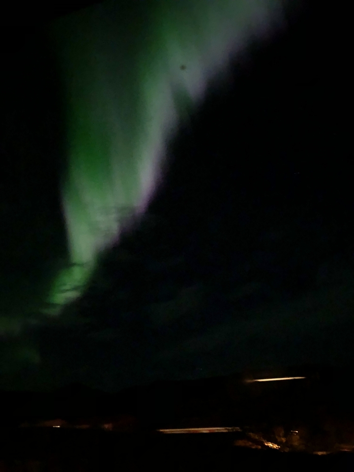Blurry view of northern lights in the night sky.