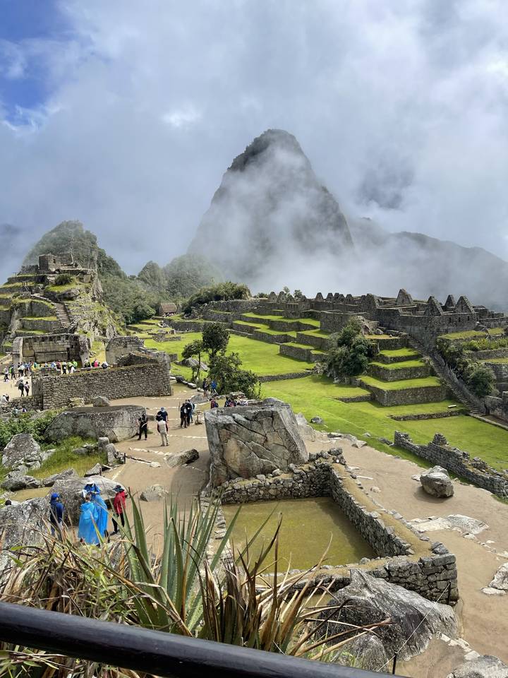 Tourists at Machu Picchu with mist and ancient ruins.