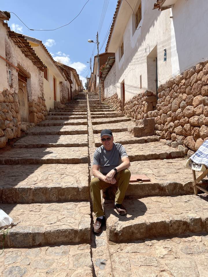 Homme assis sur les marches d'une rue étroite entre des bâtiments.