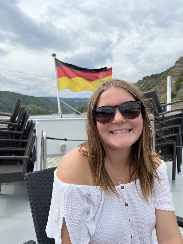Woman posing on a boat with a German flag backdrop.