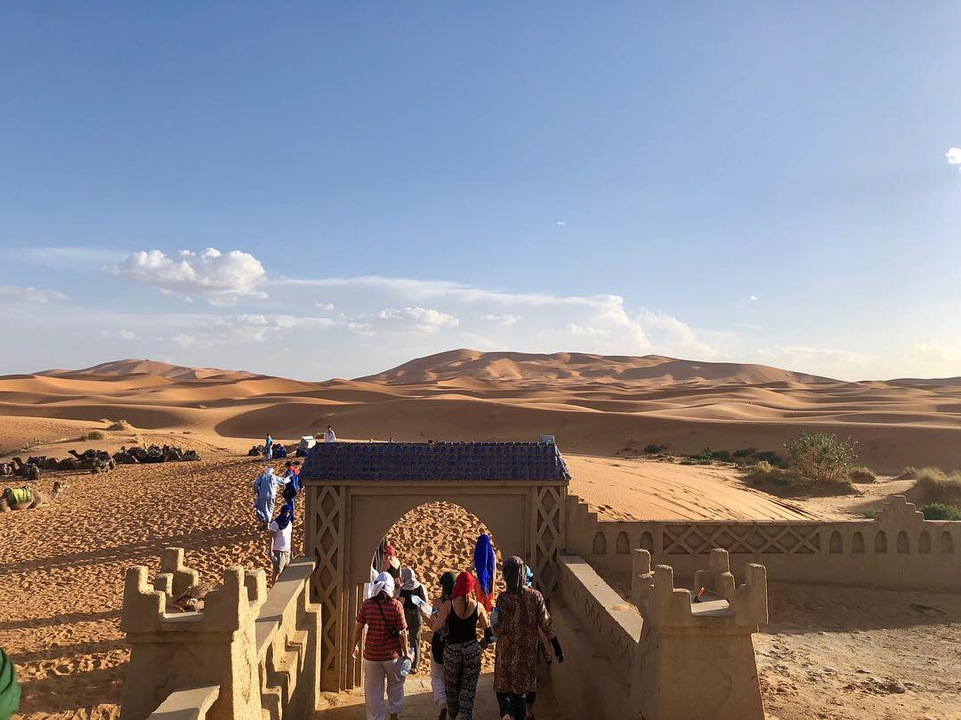 Group in traditional attire at a desert entrance.