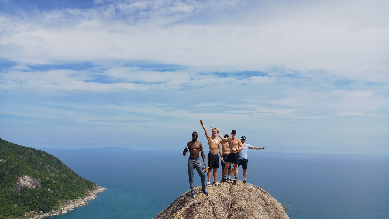 A group of people standing on a rock with a scenic ocean backdrop.