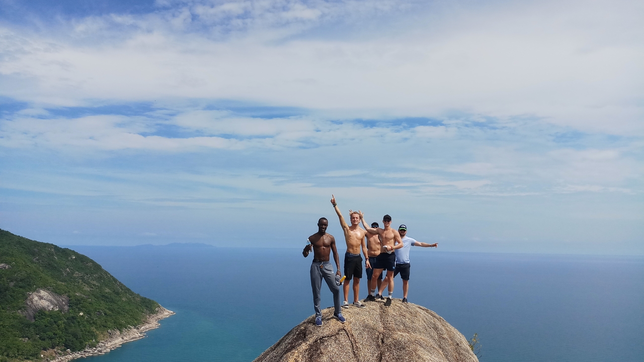 A group of people standing on a rock with a stunning ocean backdrop.