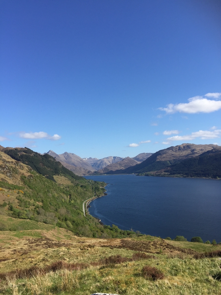 A panoramic view of a lake nestled between rolling mountains.