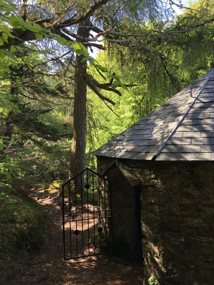 A small stone shelter in a lush, wooded area.