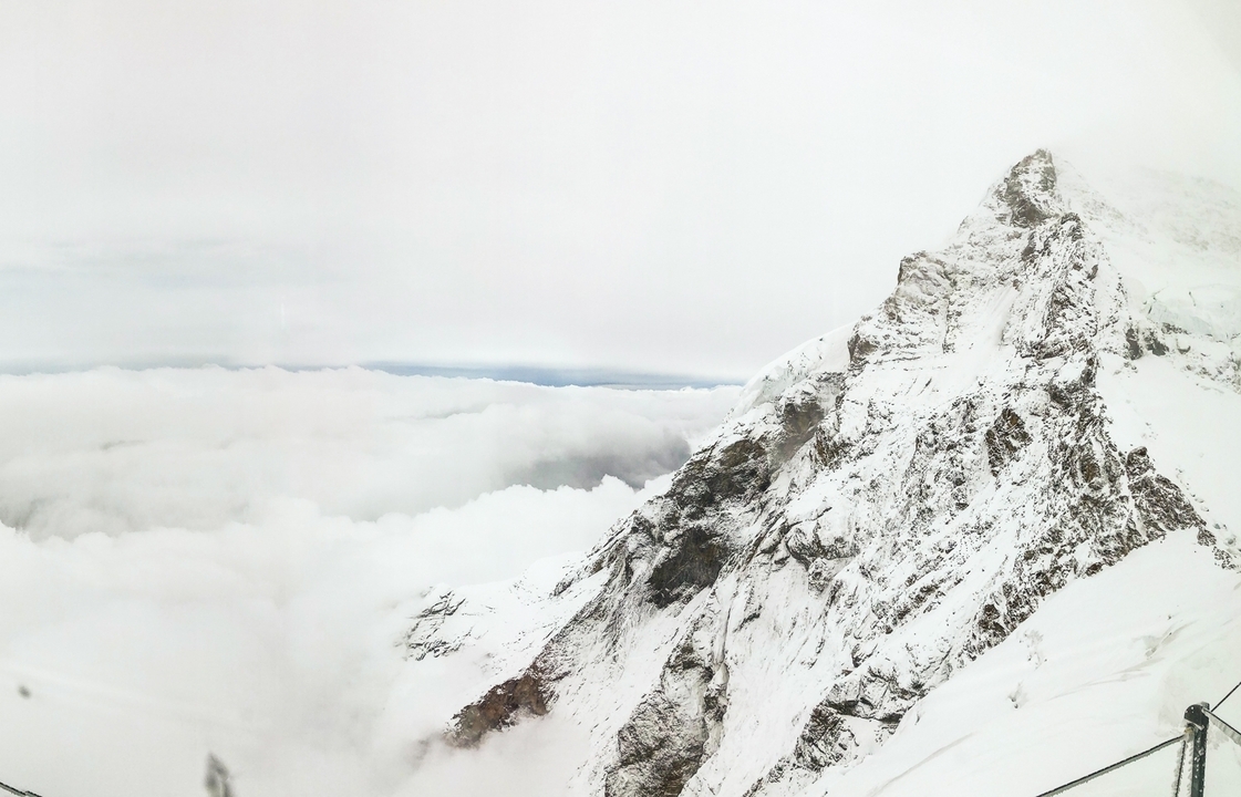 Snow-covered mountain peaks with cloudy sky.