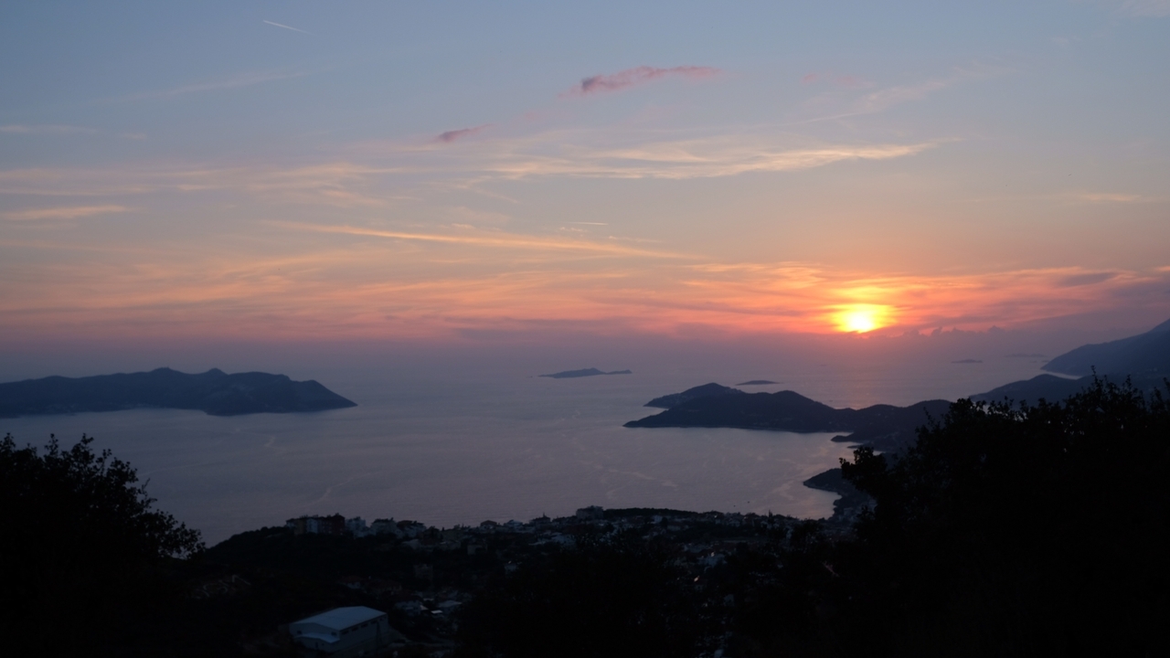 Sunset view over an expansive sea with silhouetted islands, creating a tranquil scene.
