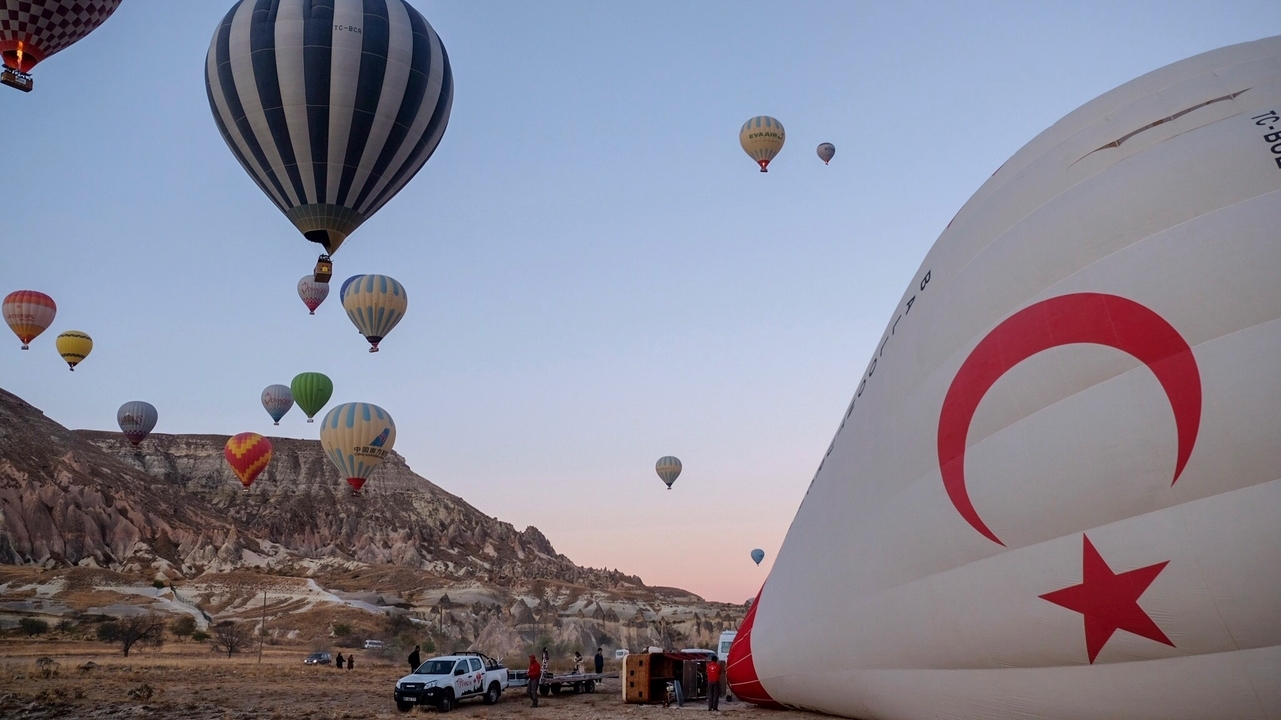 Hot air balloons floating over a rugged terrain at dawn.