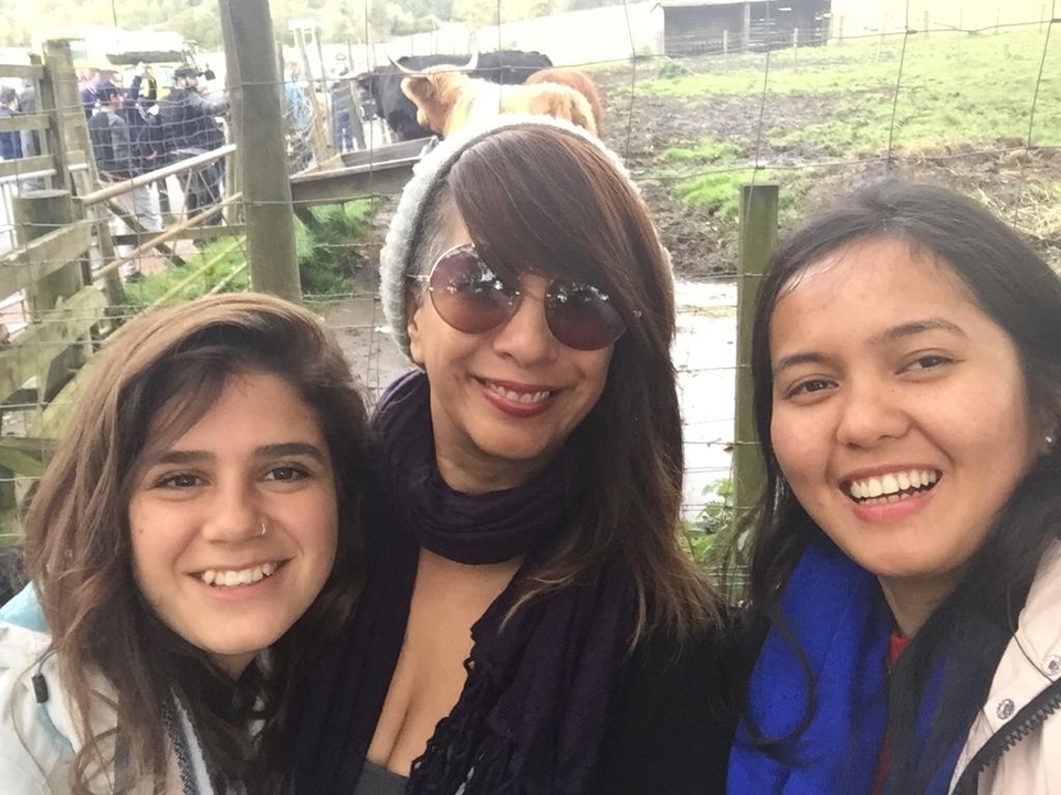 Trois femmes prennent la pose pour un selfie près d'une clôture à l'extérieur.