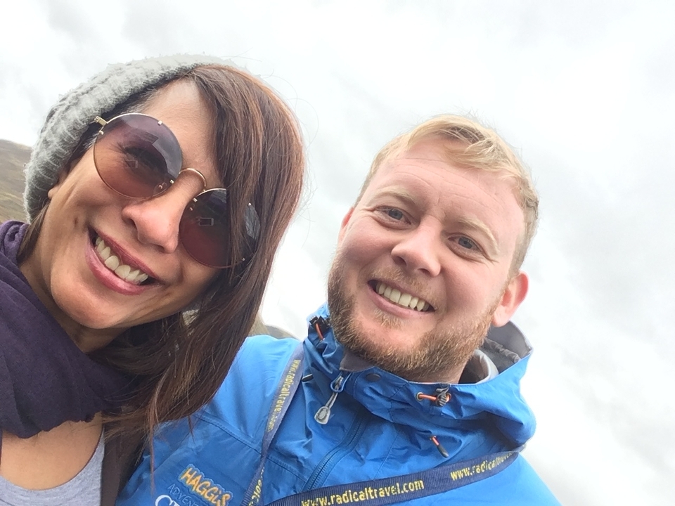 Deux personnes souriantes prenant un selfie à l'extérieur.