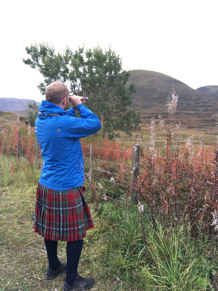 Person with a telescope in a Scottish landscape.