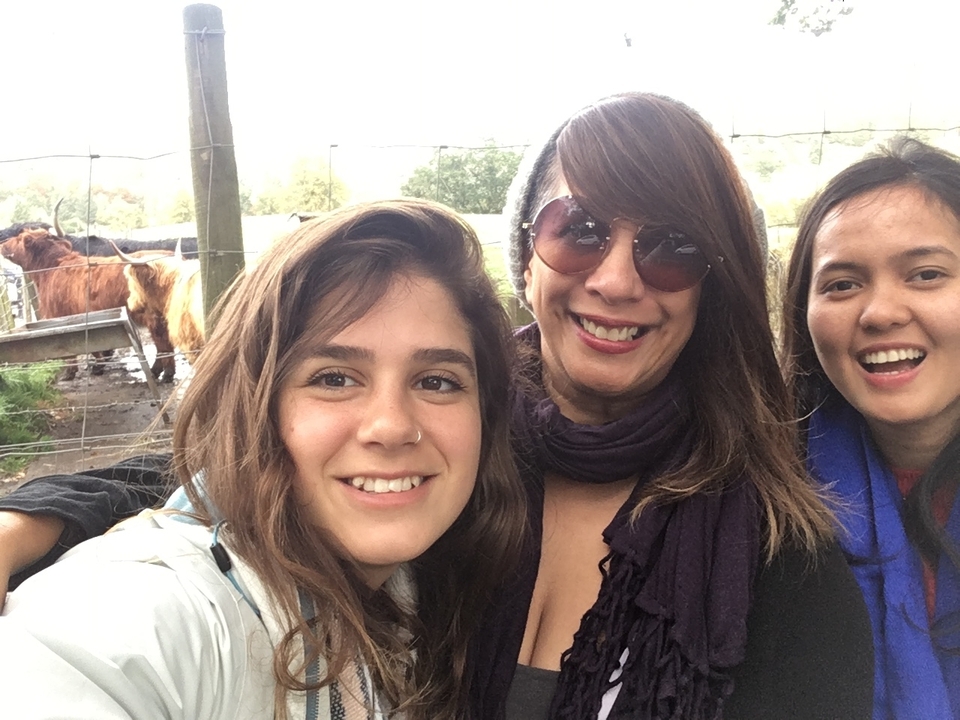 Trois femmes posant pour un selfie en extérieur près d'une clôture.