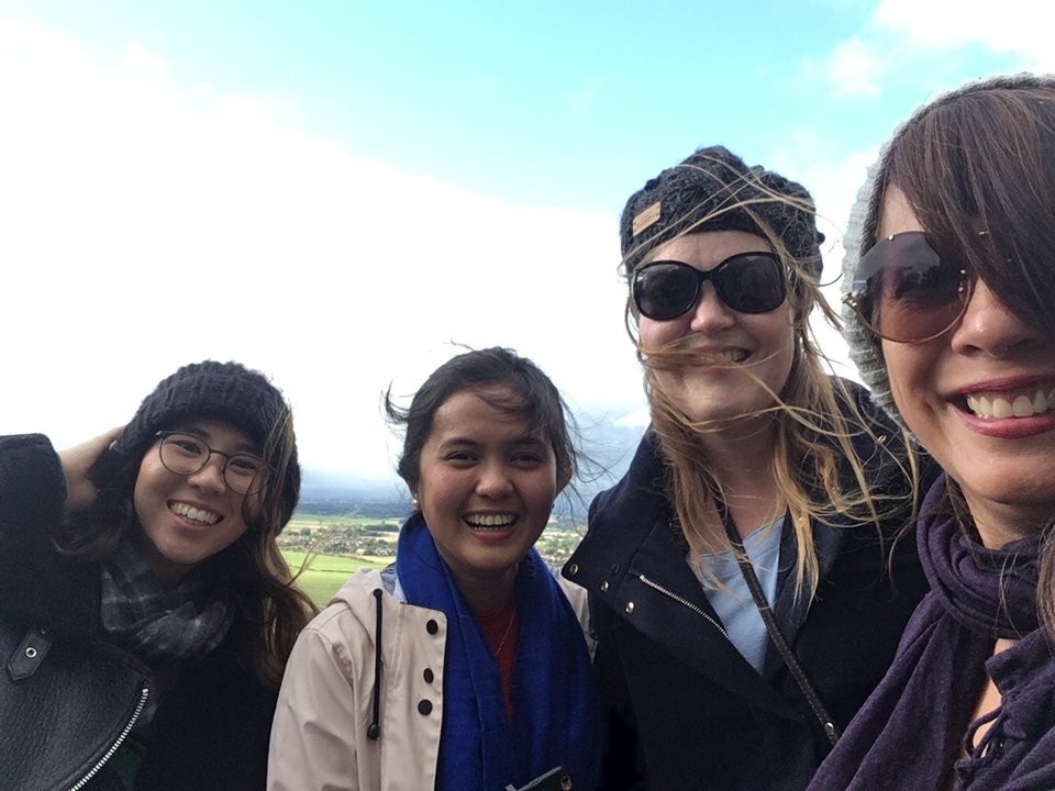 Groupe de femmes souriantes avec un paysage venteux en arrière-plan.