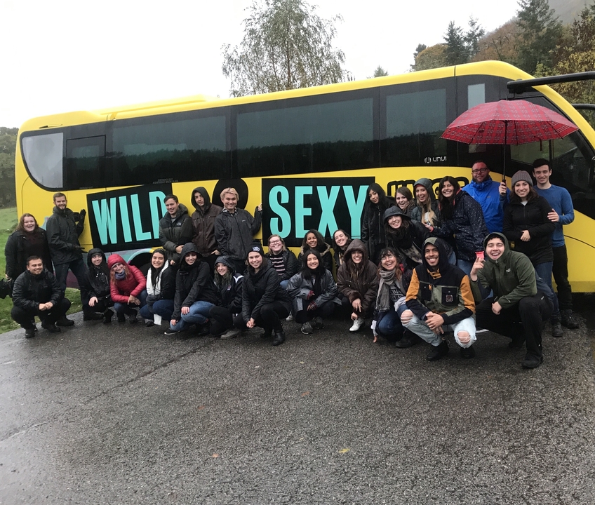 Grand groupe posant devant un bus jaune "Wild and Sexy".