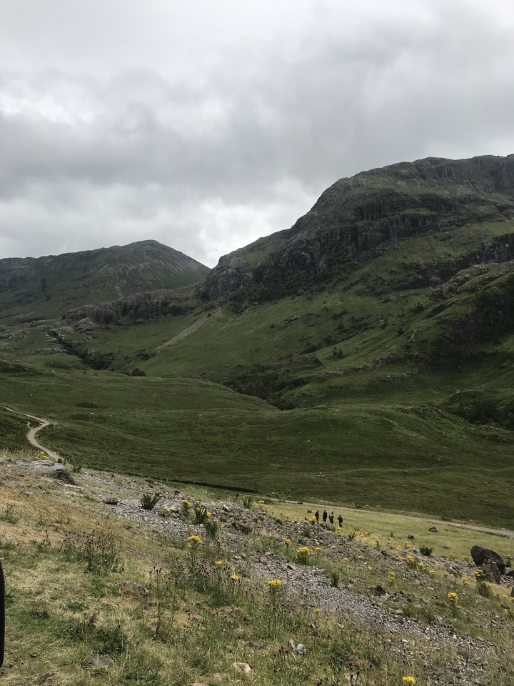 A green valley with hills under a cloudy sky.