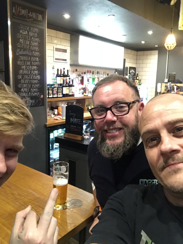 Trois hommes savourant des boissons dans un bar au cadre chaleureux.