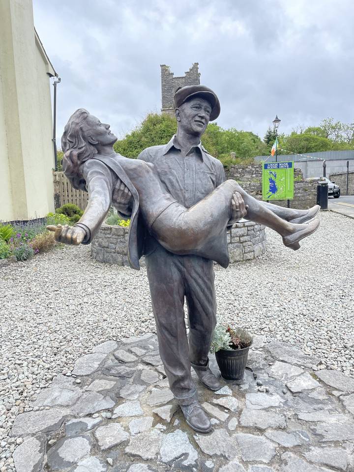 Statue of a man holding a woman in an outdoor setting.