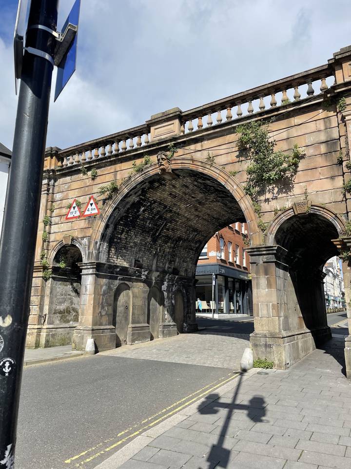 An arched stone bridge over a road.