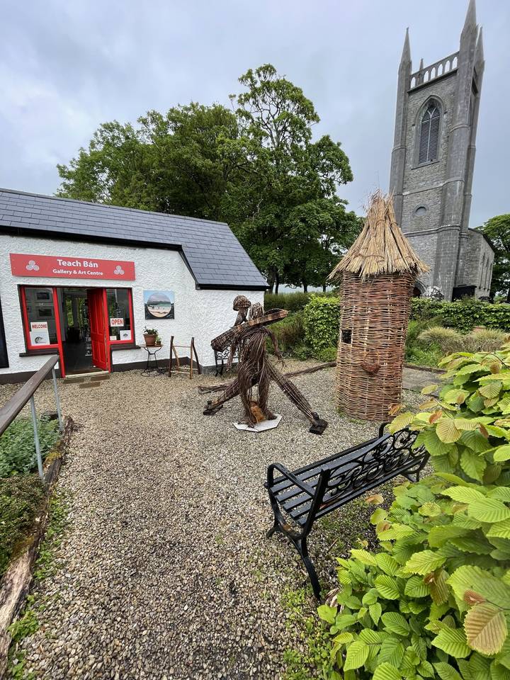 A wicker statue and small huts in a garden setting.