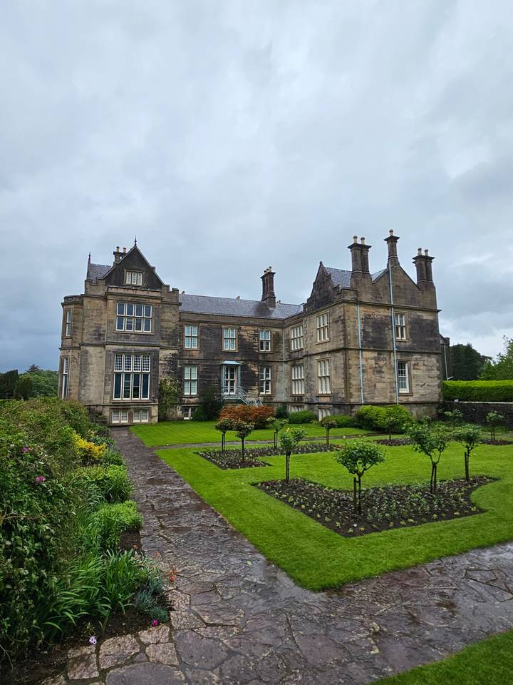 Historic building with a garden in front.