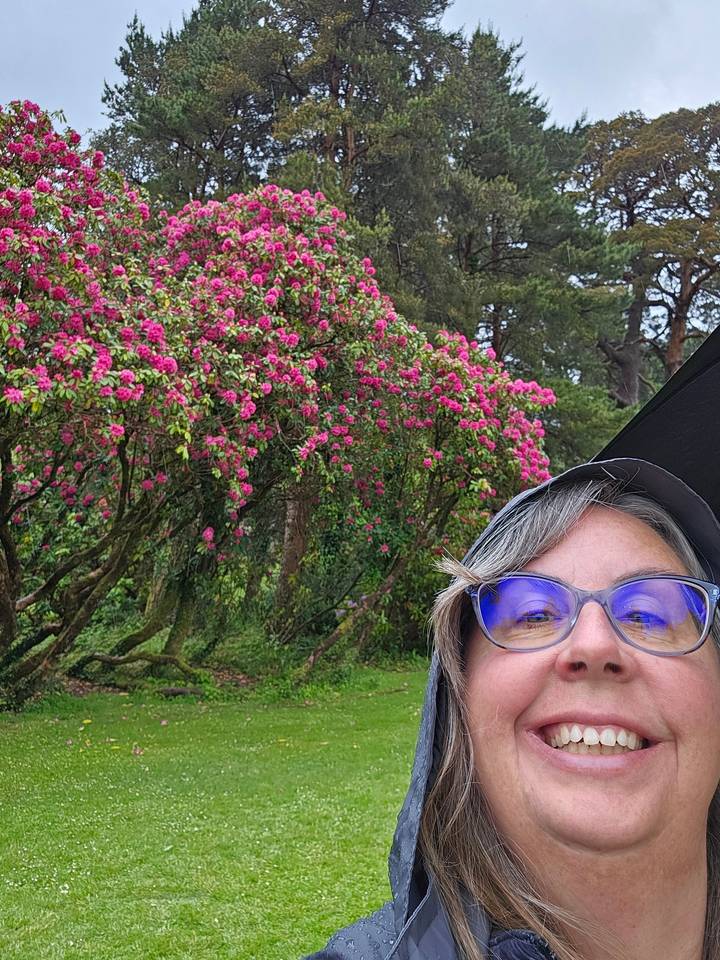 Person posing with a blooming tree.
