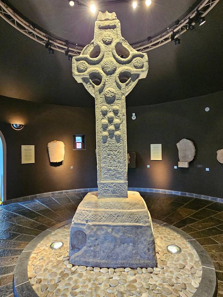 Large cross monument in a dark museum setting.